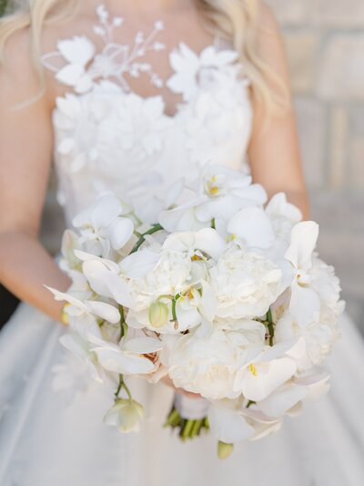 A bride holding a white bouquet of flowers.