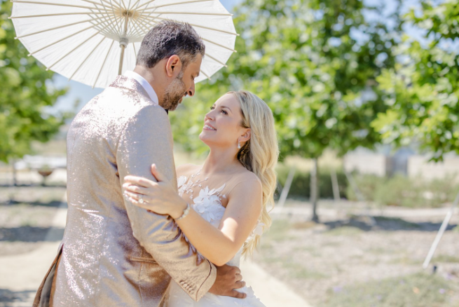 A bride and groom holding an umbrella