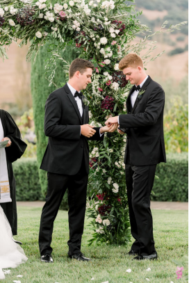 The best man hands the ring over to the groom during a destination wedding ceremony