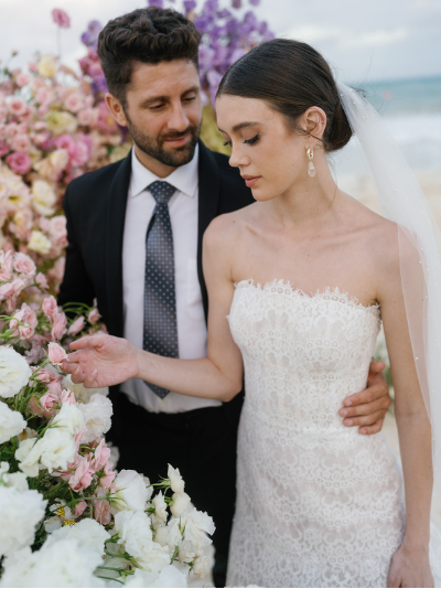 A bride and groom are posing side by side at their luxury destination wedding.