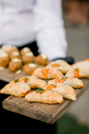 Tray of gourmet appetizers, including puff pastries topped with herbs and savory bites, served at a rehearsal dinner.