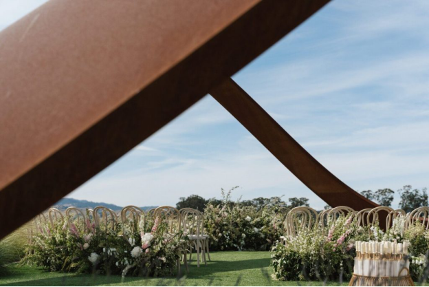 Chairs decorated with floral arrangements outdoors on a lawn