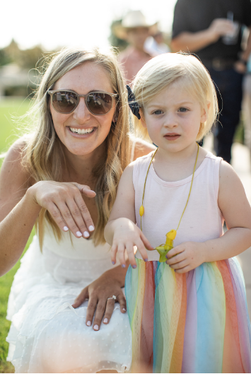 A child and her relative pose together at an outdoor luxury wedding