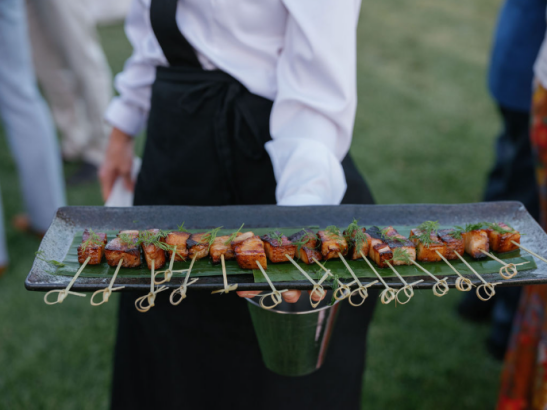 A server presenting elegantly plated gourmet skewers