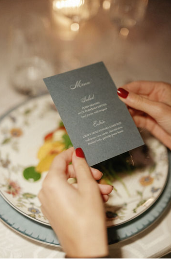 A custom menu displayed against a dish in fine china at a luxury wedding