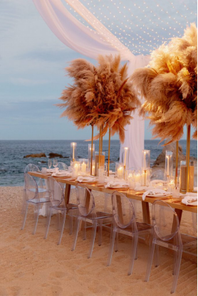 Beachfront dinner setting with pampas, grass centerpieces, and soft candlelight