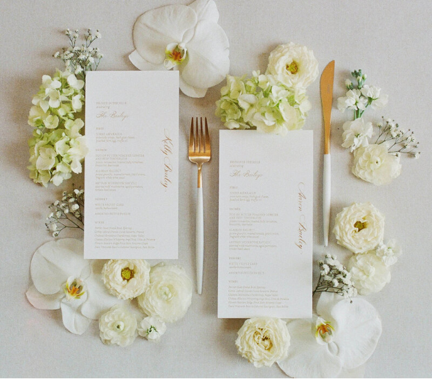 Elegant wedding menu with floral arrangements and gold-accented cutlery