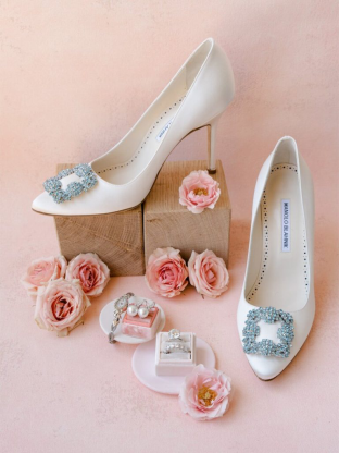 Chic bridal heels adorned with embellishments surrounded by delicate pink florals and elegant jewelry