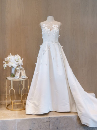 A beautifully detailed white gown with floral embellishments paired with chic accessories on display
