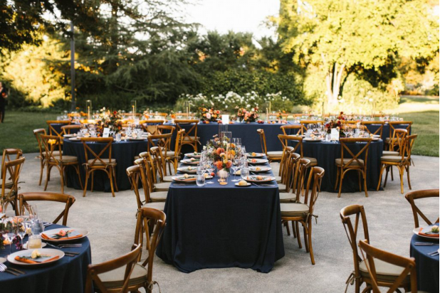Outdoor wedding reception with navy blue table settings and floral centerpieces