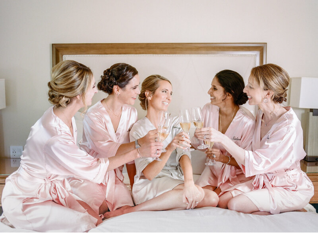 Bridal party toasting with champagne in matching robes before the wedding