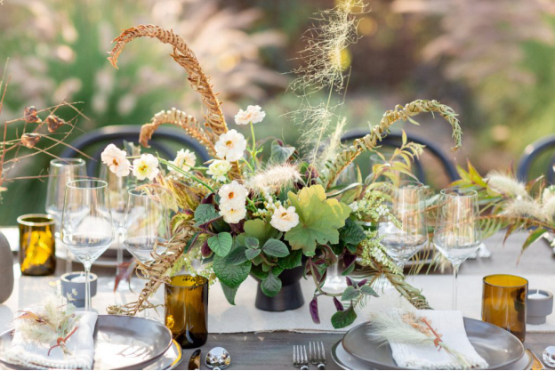 Rustic floral centerpiece with earthy tones and natural elements on a wedding dining table.