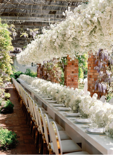 A long dinner table with flowers hanging above