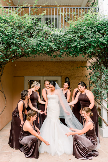 Bride in an elegant wedding gown surrounded by her bridesmaids in a beautifully lit New York City venue, capturing a moment of refined celebration