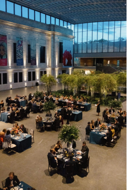 Guests seated at round tables in an elegant indoor Washington, DC venue featuring natural greenery and floor-to-ceiling windows during the wedding reception.