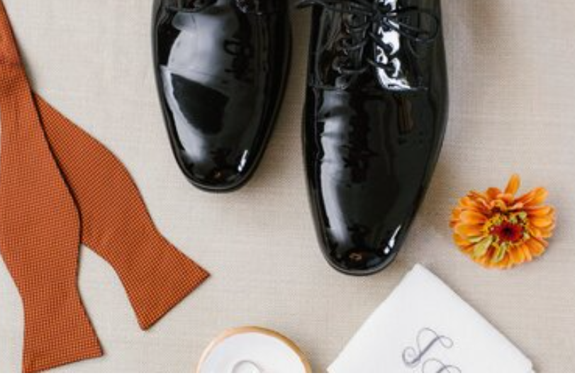 Close-up of polished black dress shoes and a classic black bow tie on a suit.