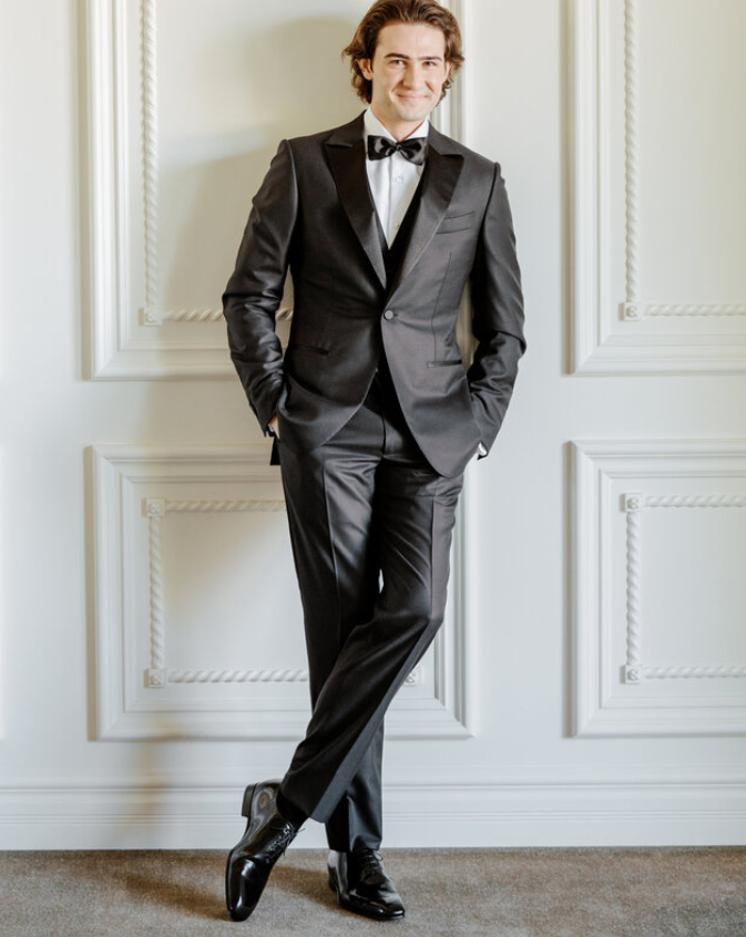 Man wearing black dress shoes and a tuxedo, ready for a formal event.
