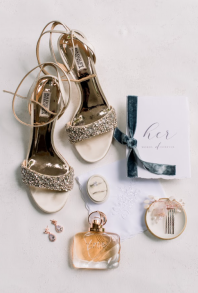 Close-up of bridal accessories including earrings, a hairpin, and perfume.
