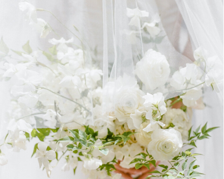 A bride wearing a delicate veil that flows behind her in natural light.