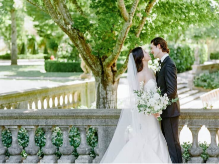 A bride in a full-skirted wedding gown standing in an open, elegant venue.