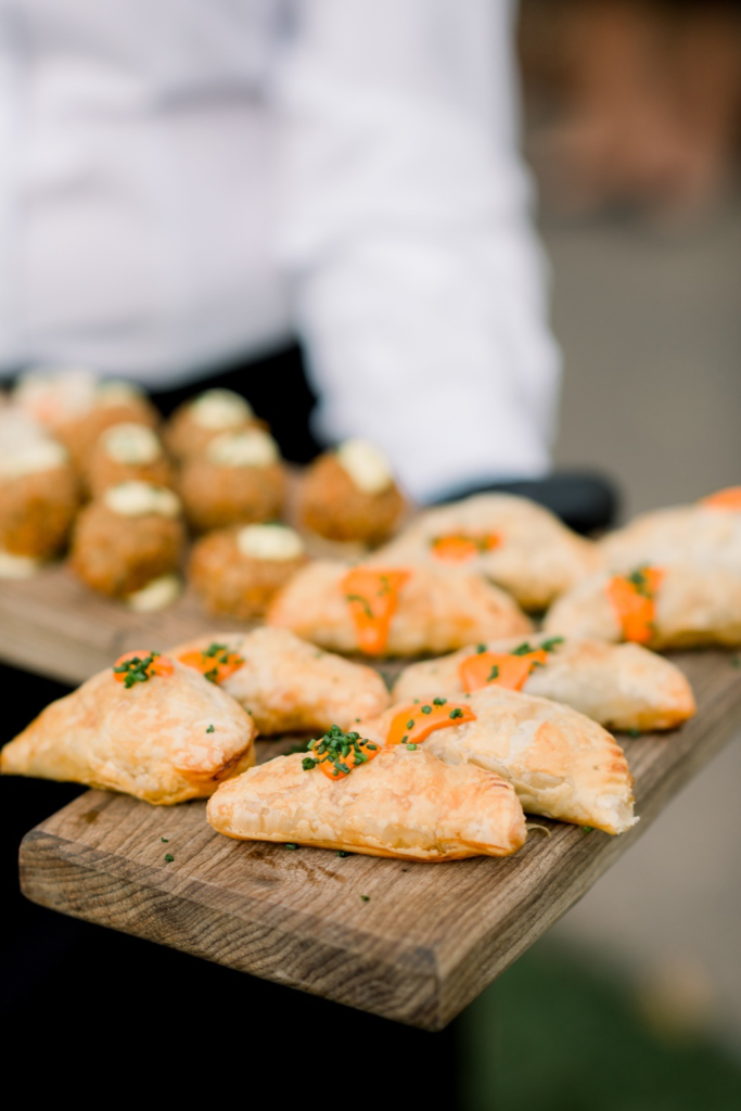 A waiter serves trays of empanadas and meatballs, offering savory bites during the rehearsal dinner