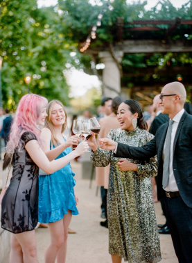 Guests enjoying a lively outdoor cocktail hour, raising glasses in celebration at a wedding planned by Emily Coyne Events