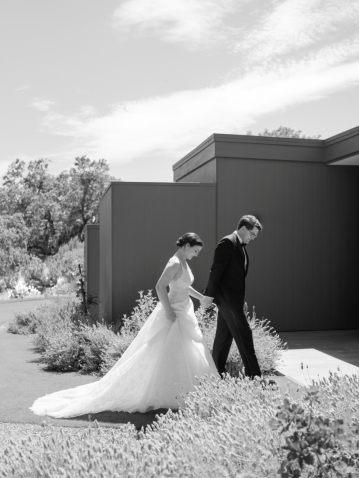 a bride and groom walking holding hands.