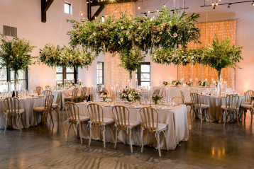 An image of floral arrangements above tables during an indoor wedding