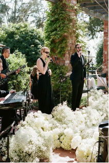 An image of a stage decorated with white flowers as singers perform