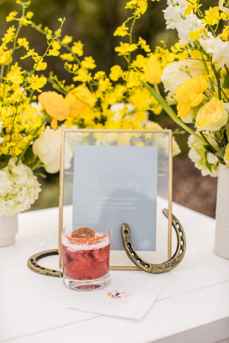 a red drink next to yellow flowers. 