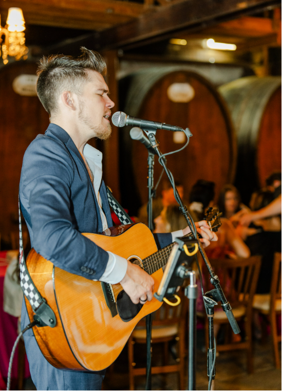 Male musician in a suit playing guitar and singing at a wedding reception