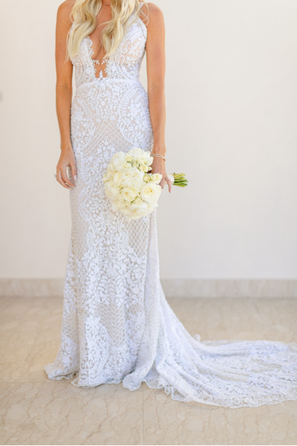 a bride holding a bouquet of white roses.