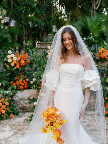 a bride in a veil holding flowers.