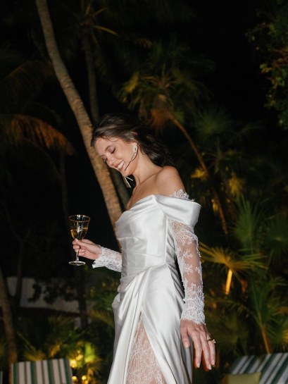a bride in a white gown holding a drink.