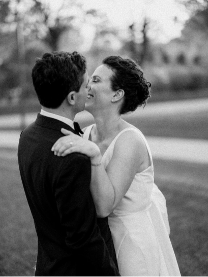Black and white close-up shot of a bride laughing while the groom looks at her lovingly, showing an intimate, emotional wedding moment